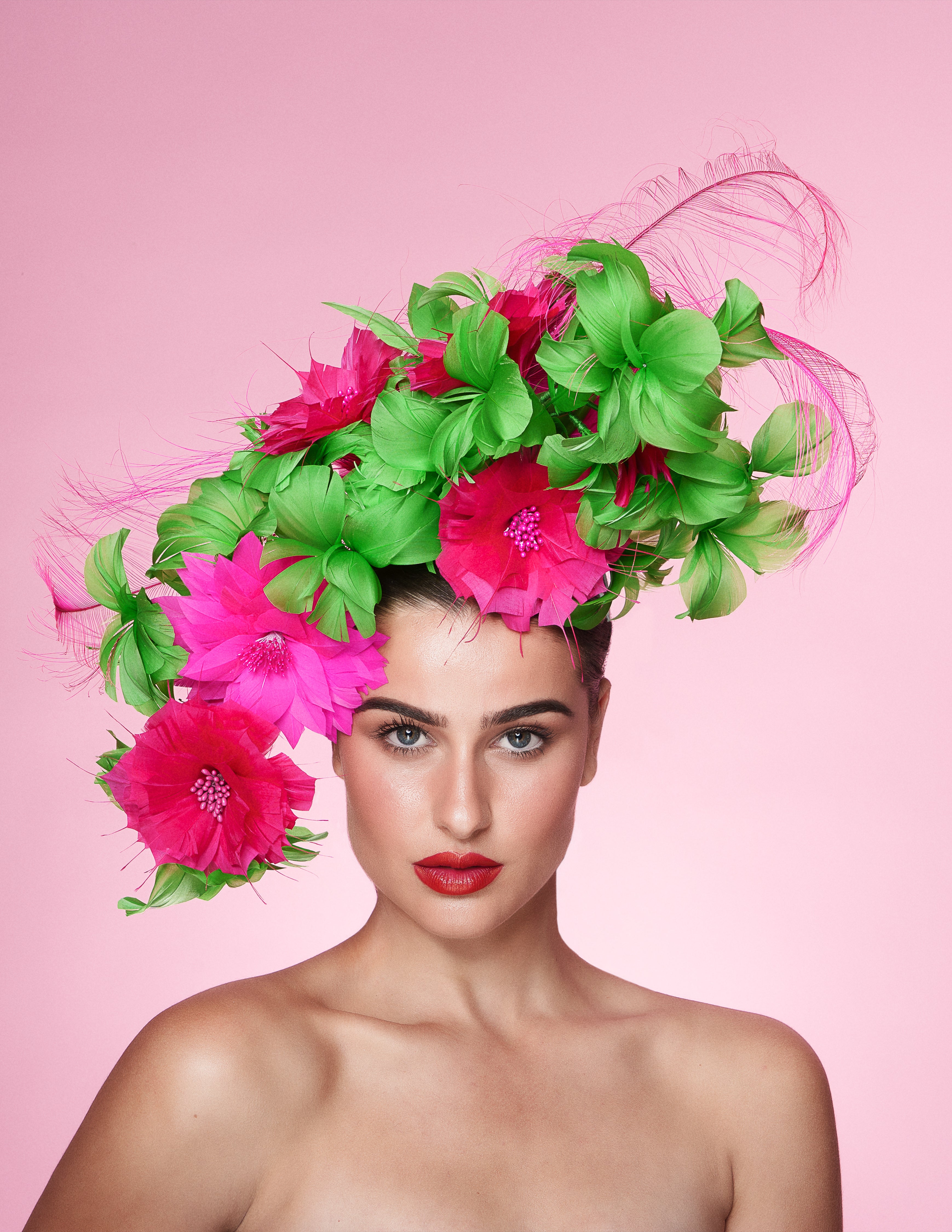 Woman with a vibrant floral headpiece against a pink background