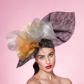 Woman wearing a decorative hat with large flowers on a pink background