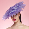 Woman wearing a purple feathered hat against a pink background