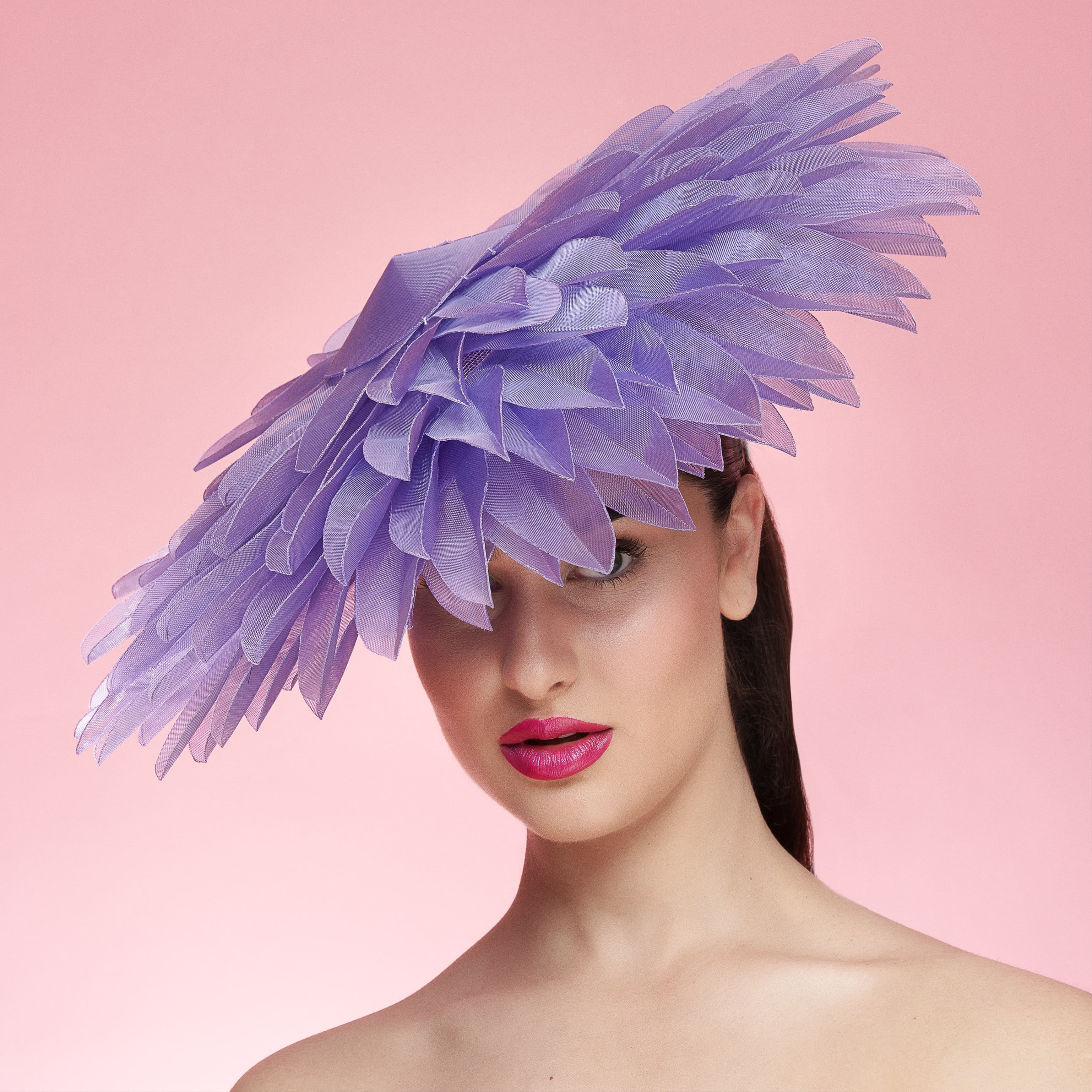Woman wearing a purple feathered hat against a pink background