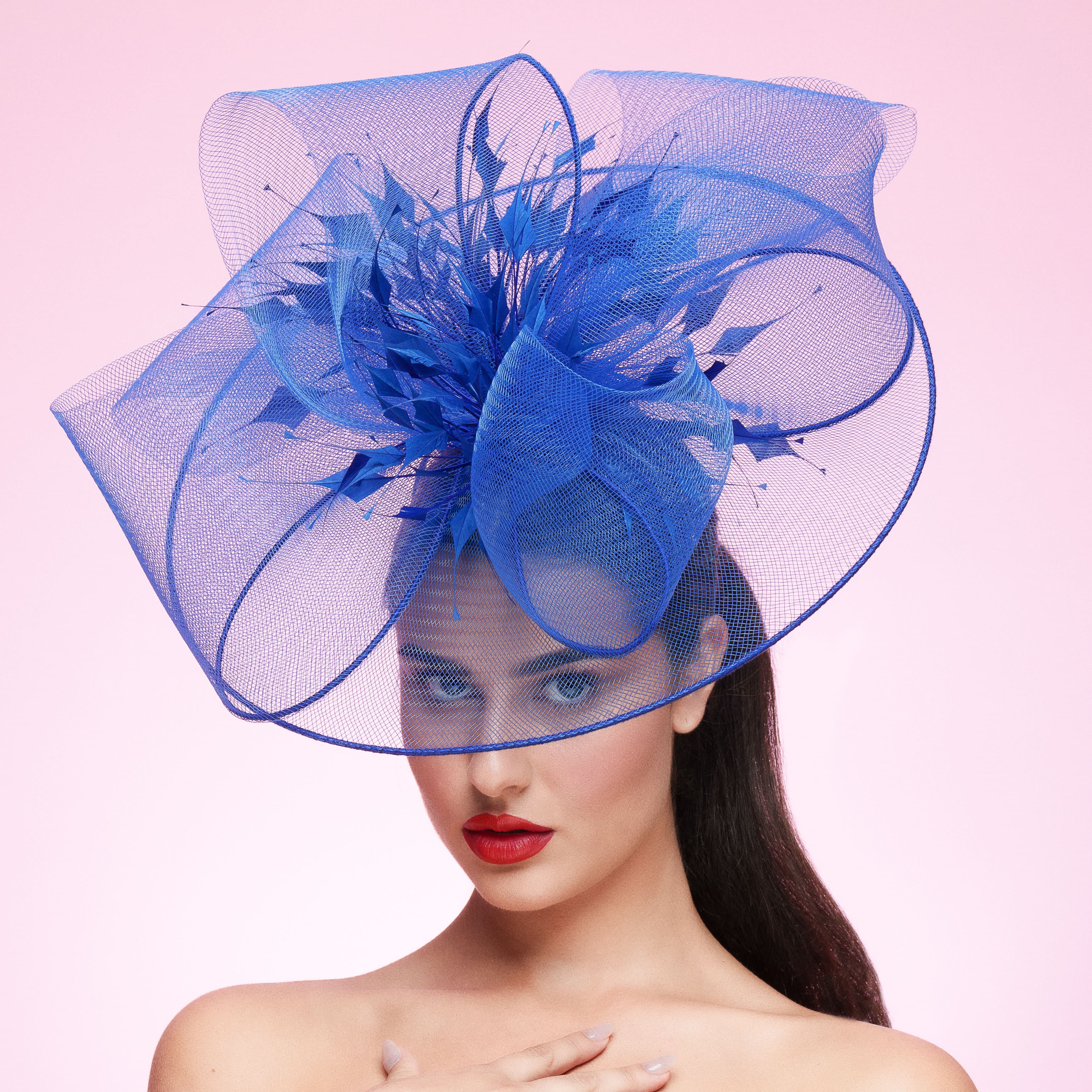 Woman wearing a large blue decorative hat against a pink background