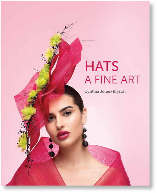 Book cover of 'Hats: A Fine Art' with a model wearing a decorative hat on a pink background
