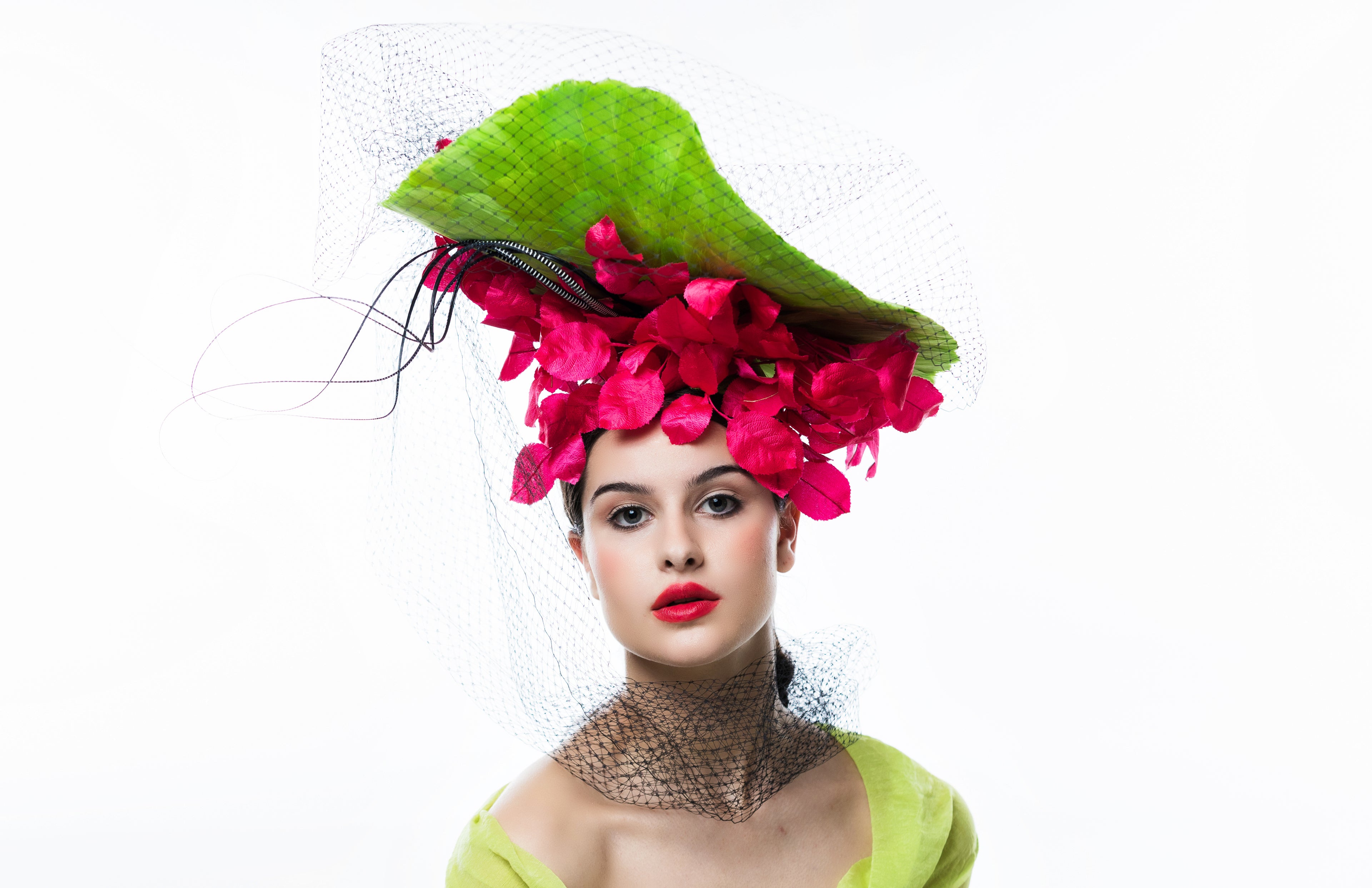 Woman wearing a vibrant green hat with pink flowers on a white background